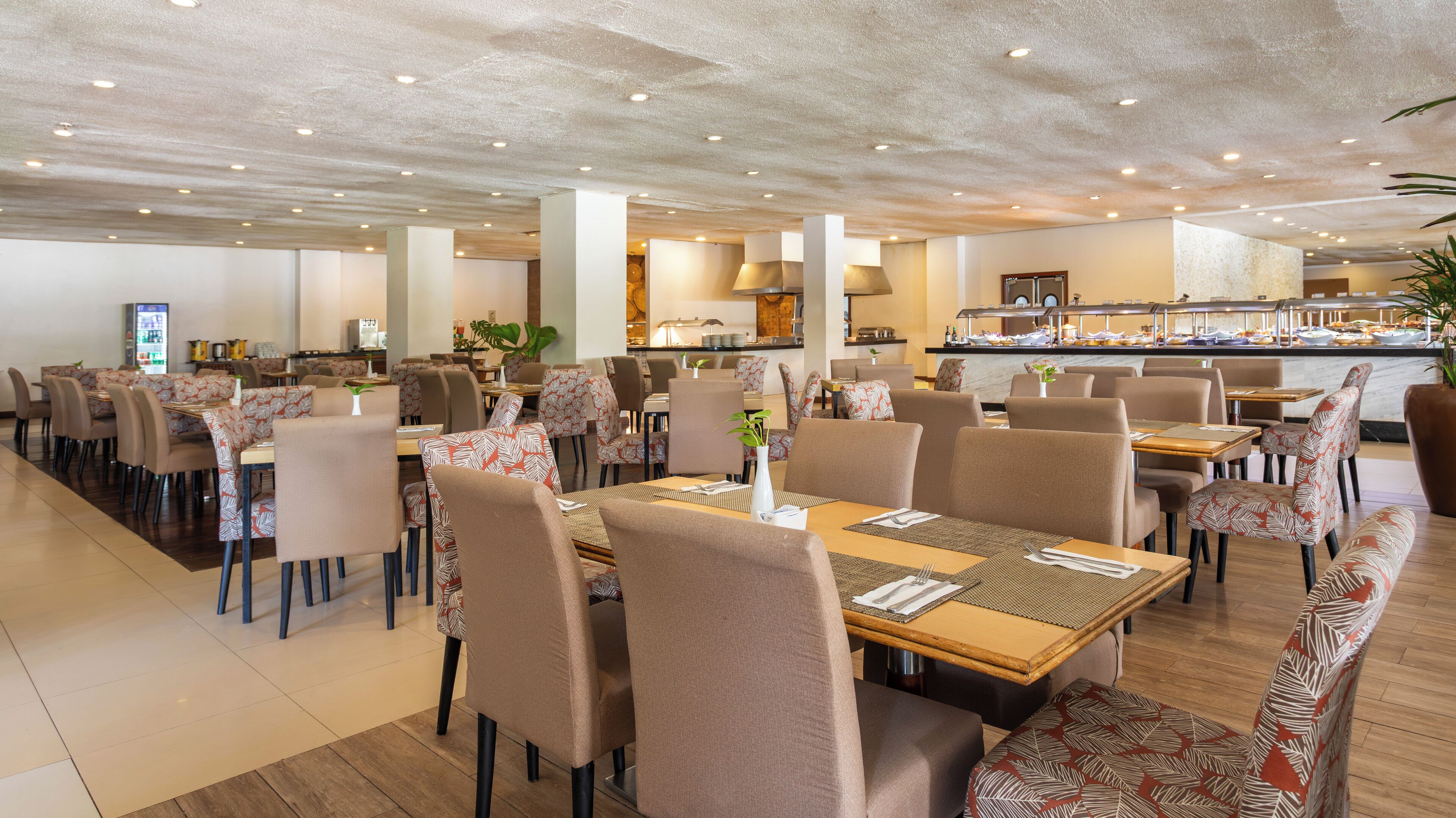 Un grand espace dédié à la salle à manger, avec plusieurs tables et chaises, un buffet et une cuisine en arrière-plan.