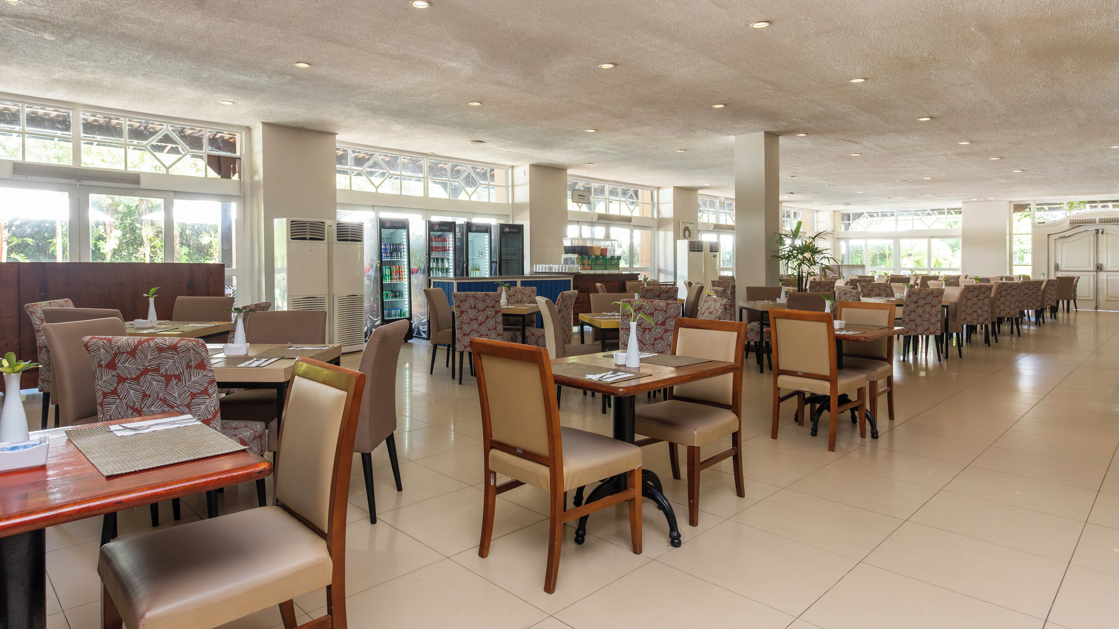 Un vaste espace dédié à la restauration, avec de nombreuses tables et chaises, de grandes fenêtres et des distributeurs automatiques.
