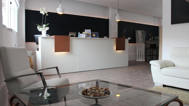 Un salon moderne avec une table basse en verre, des canapés blancs et un espace d’accueil agrémenté d’un mur d’accent noir.