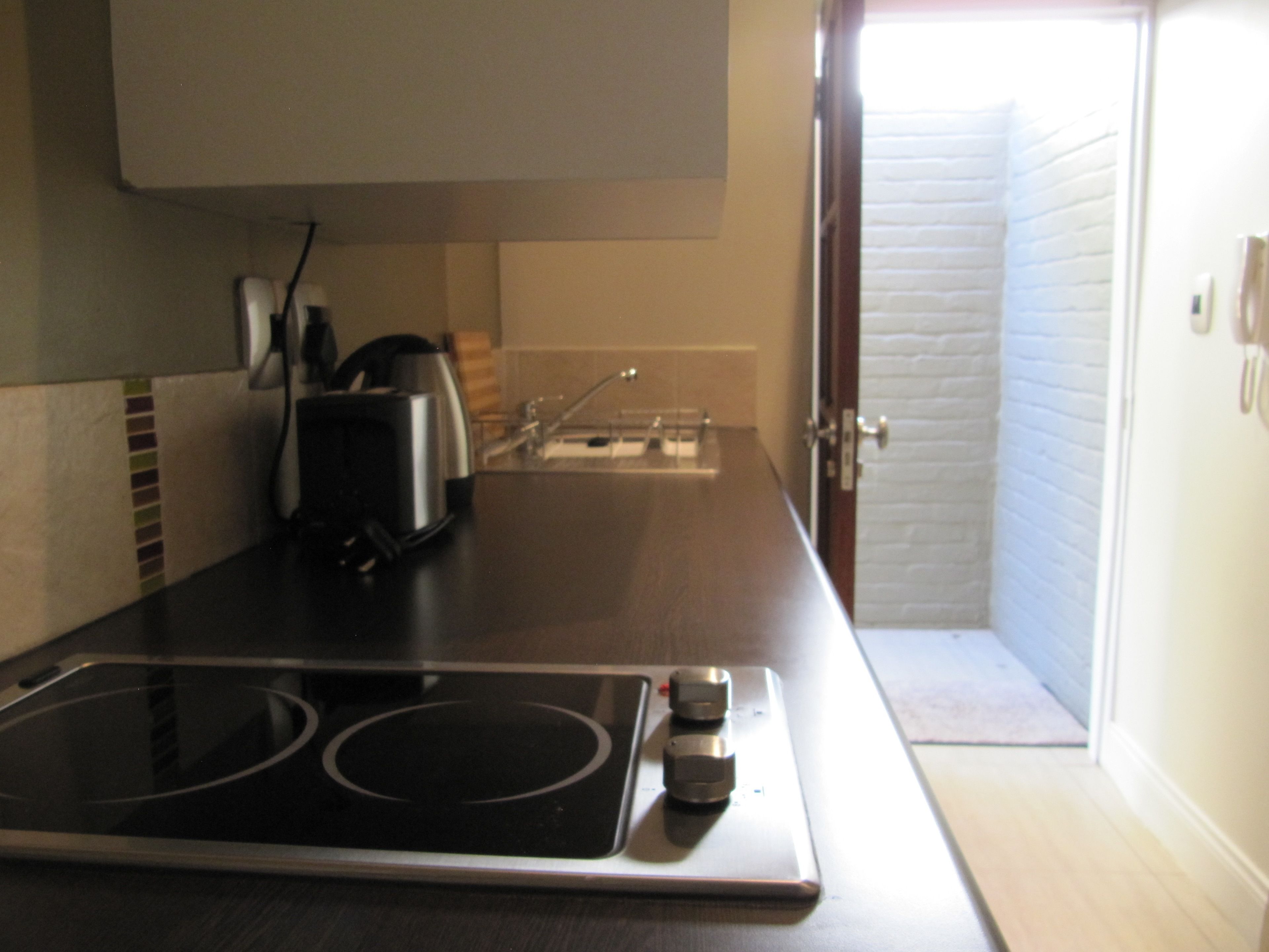 A kitchen with an induction cooktop, a toaster, and a sink.