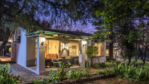 A modern house with a covered porch, a dining area, and a garden. - The Haystack on Homestead (Sandton)