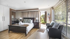 A modern bedroom with a large bed, bedside tables, a desk, and a window with blinds. - The Haystack on Homestead (Sandton)