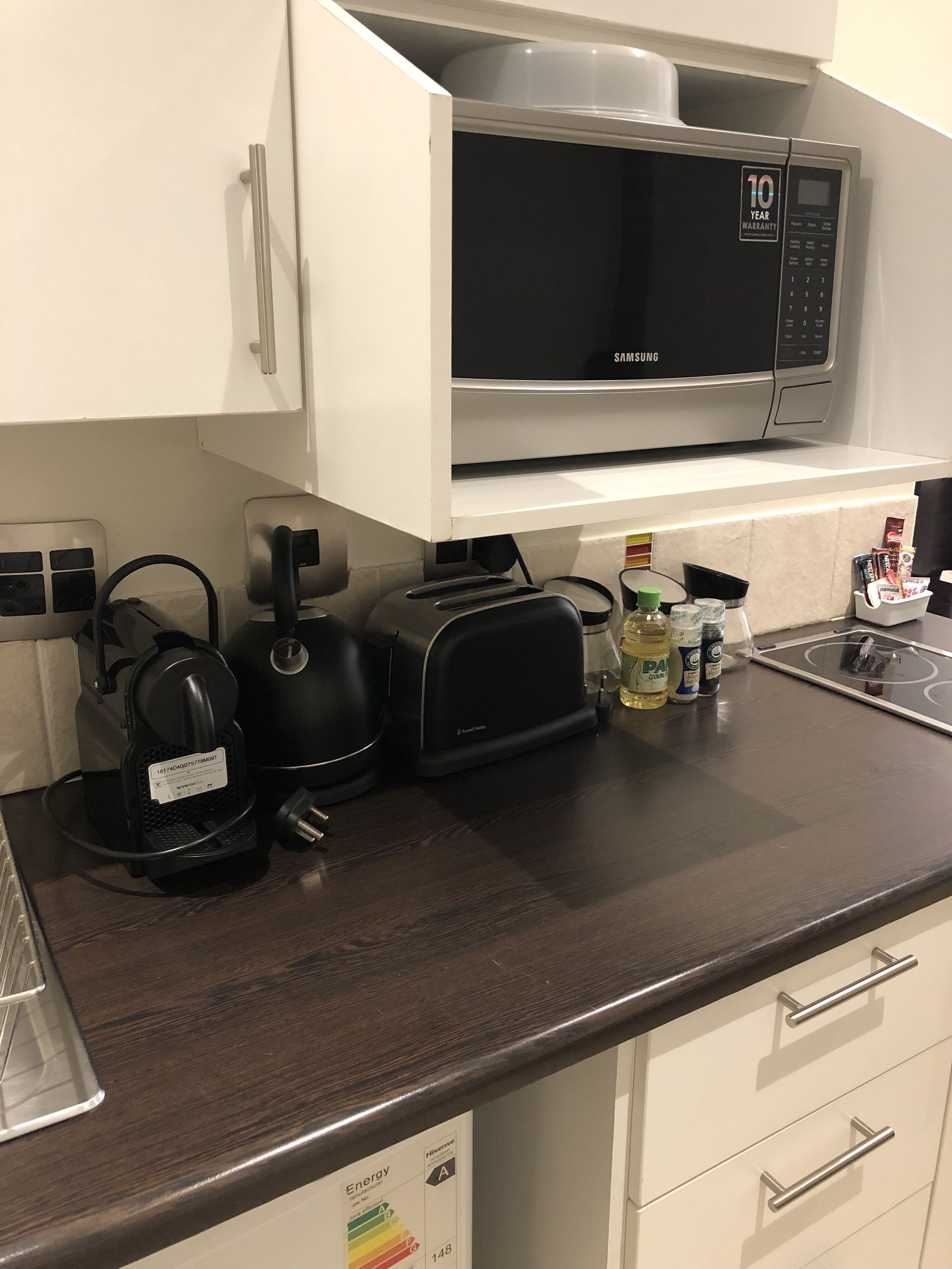 Una cocina equipada con microondas, tostadora, hervidor y varios electrodomésticos.