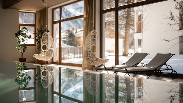 Una piscina interior con dos sillones de relax y dos lámparas decorativas colgantes.