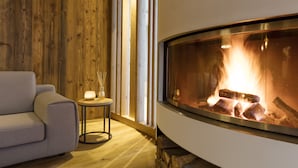Una habitación acogedora con una chimenea moderna, un sofá confortable y una mesita con velas.