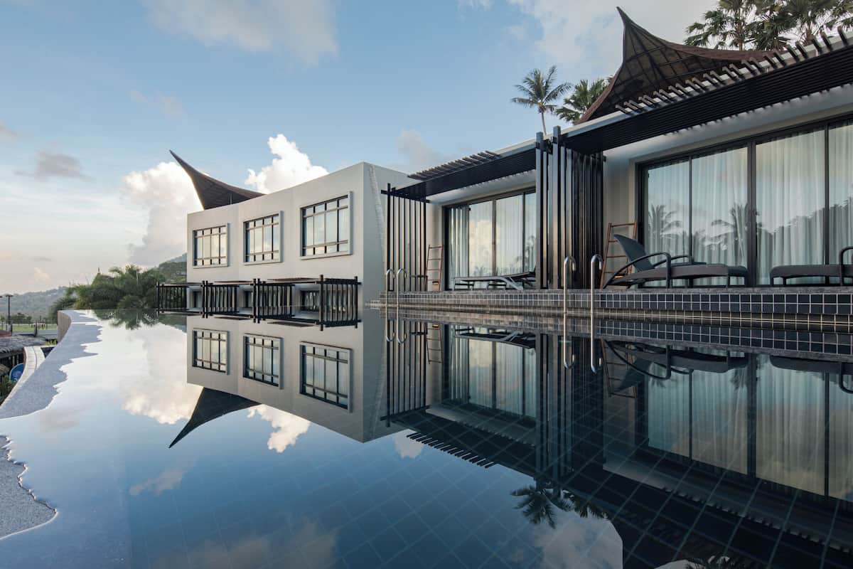 A modern hotel with a reflective pool, large windows, and a traditional roof design.