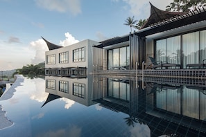 A modern hotel with a reflective pool, large windows, and a traditional roof design. - The Tarna Resort, Koh Tao (Koh Tao)