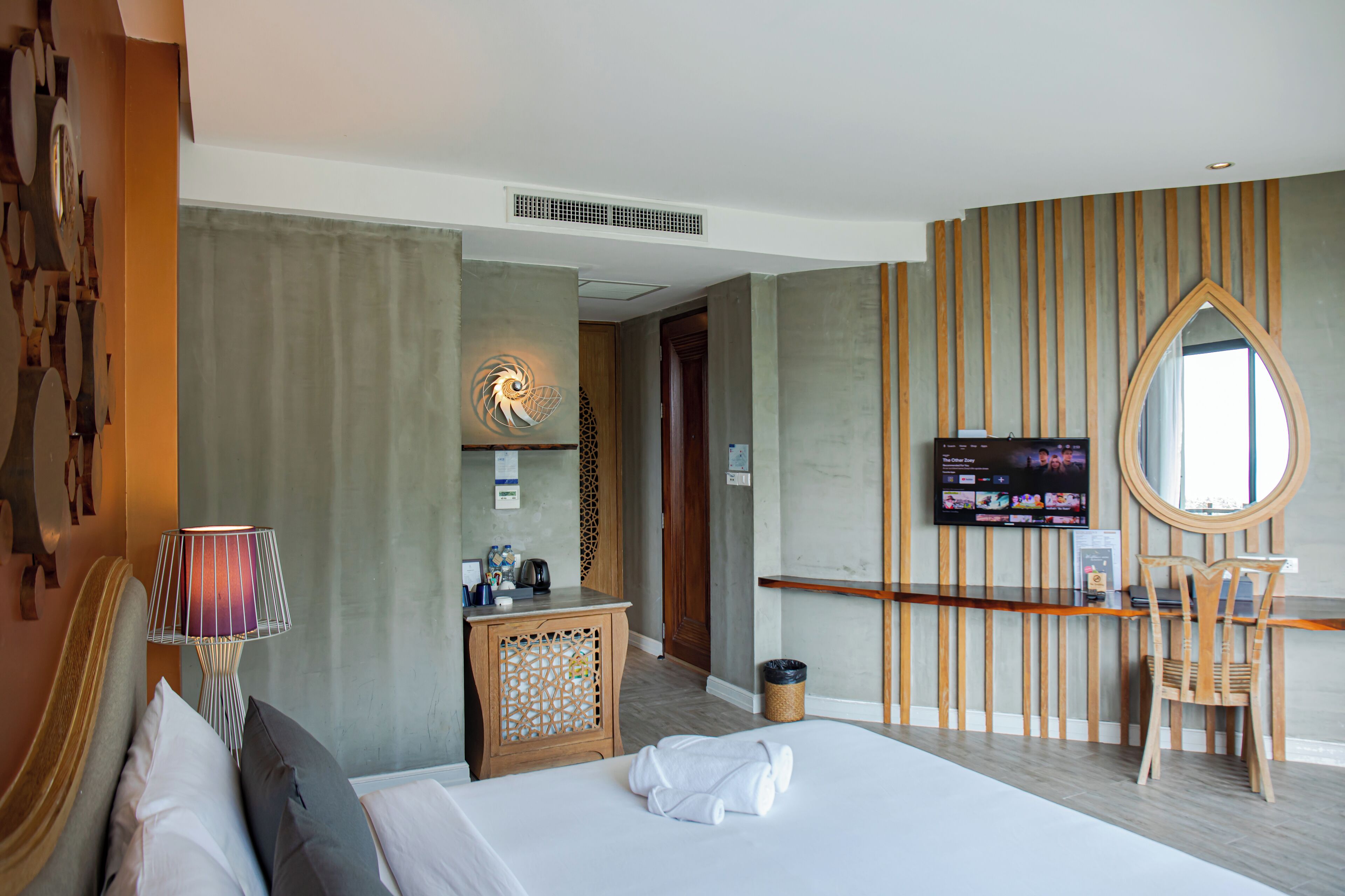 Una habitación de hotel con cama, escritorio, televisor y espejo.