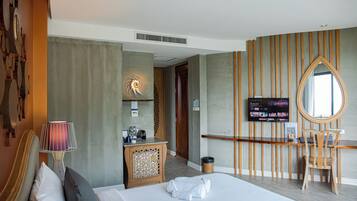 Una habitación de hotel con cama, escritorio, televisor y espejo.
