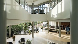 A spacious atrium with a central staircase, multiple levels, and potted plants. - The Tarna Resort, Koh Tao (Koh Tao)