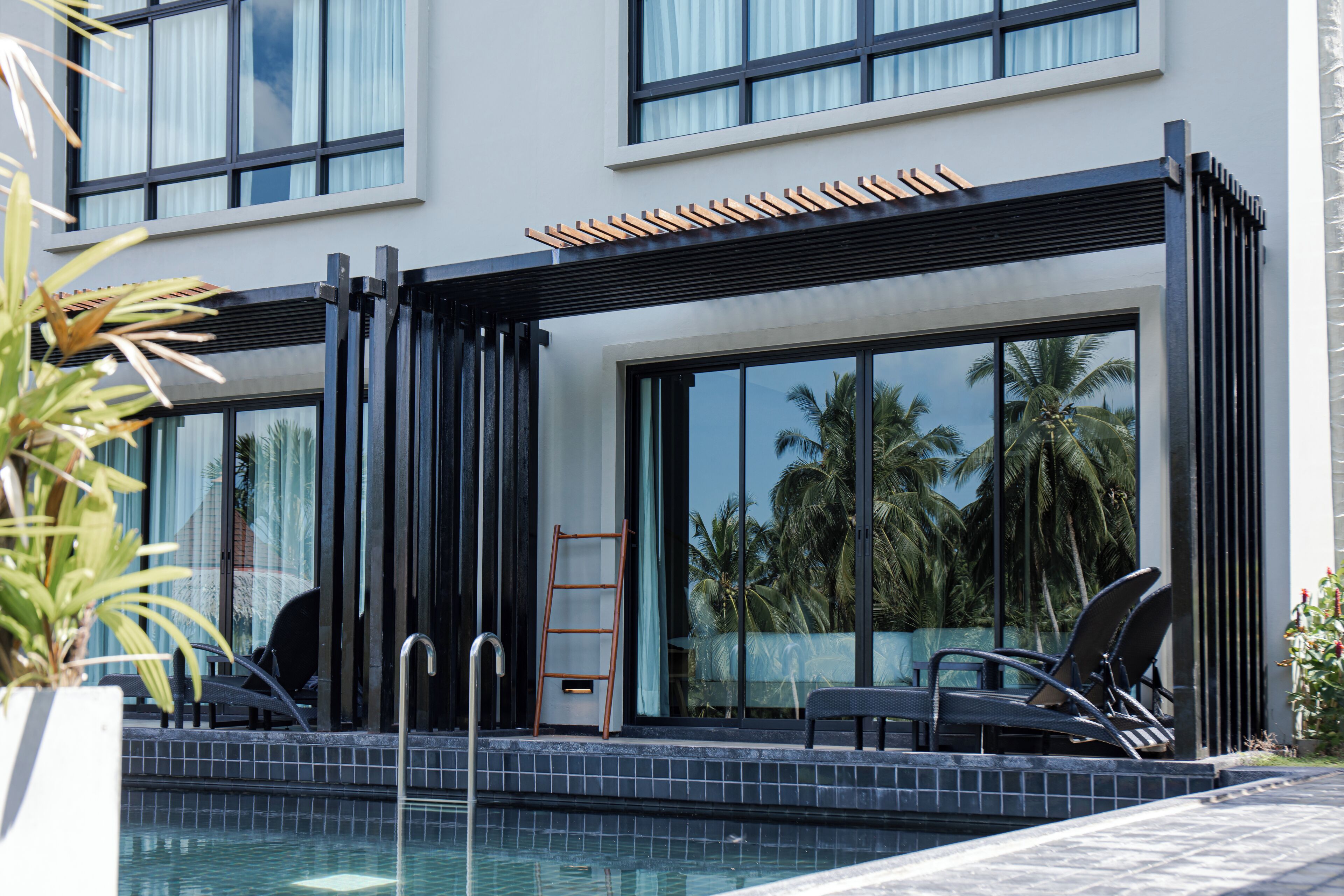 Ein Poolbereich eines modernen Hotels mit einer Glaskuppel-Kabine, Liegestühlen und einer Leiter.
