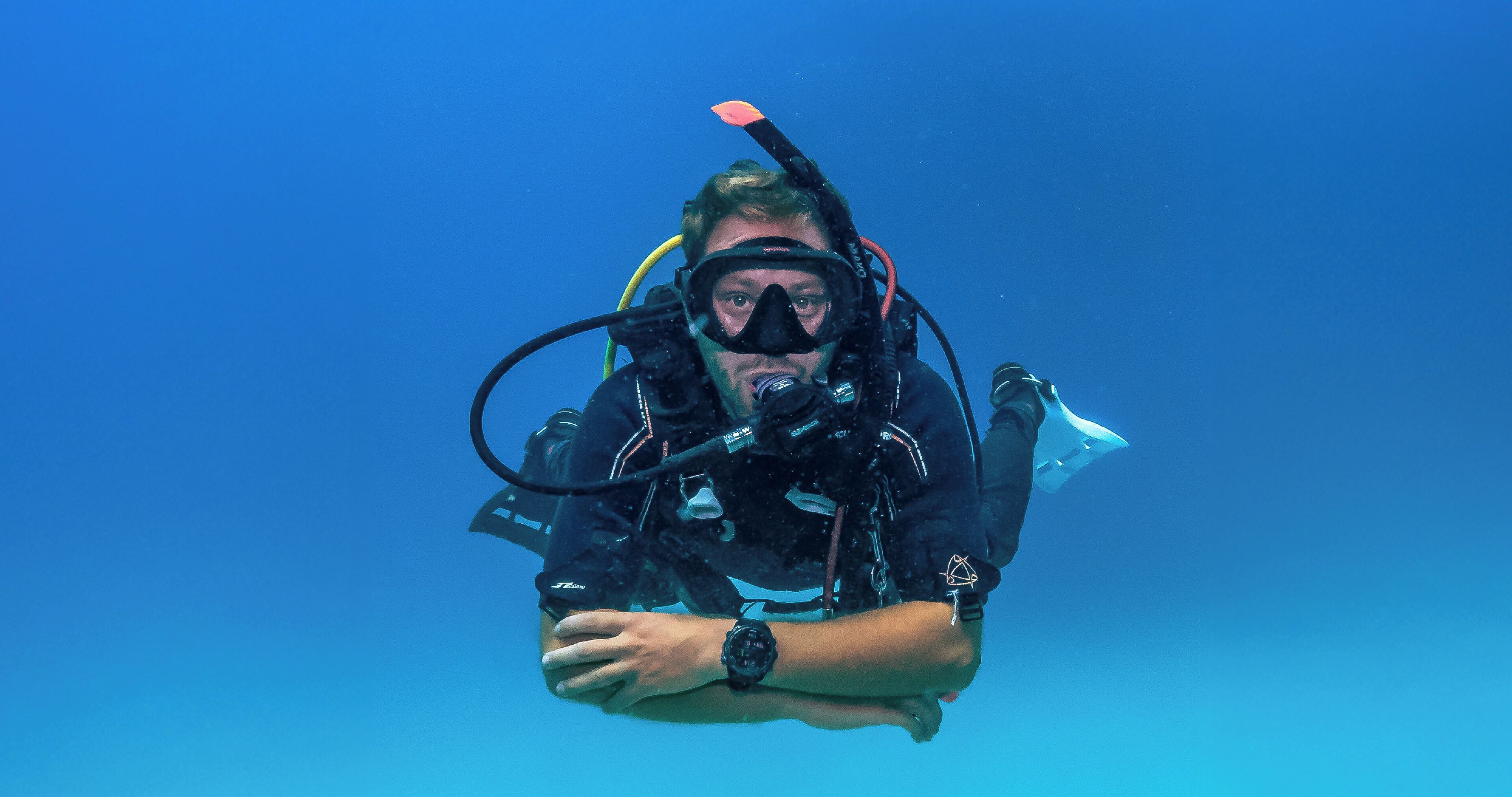 A person scuba diving with a black wetsuit and a watch.