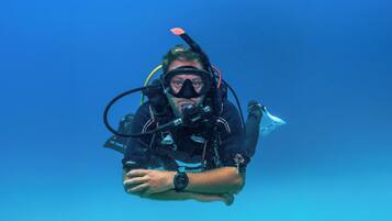 A person scuba diving with a black wetsuit and a watch.