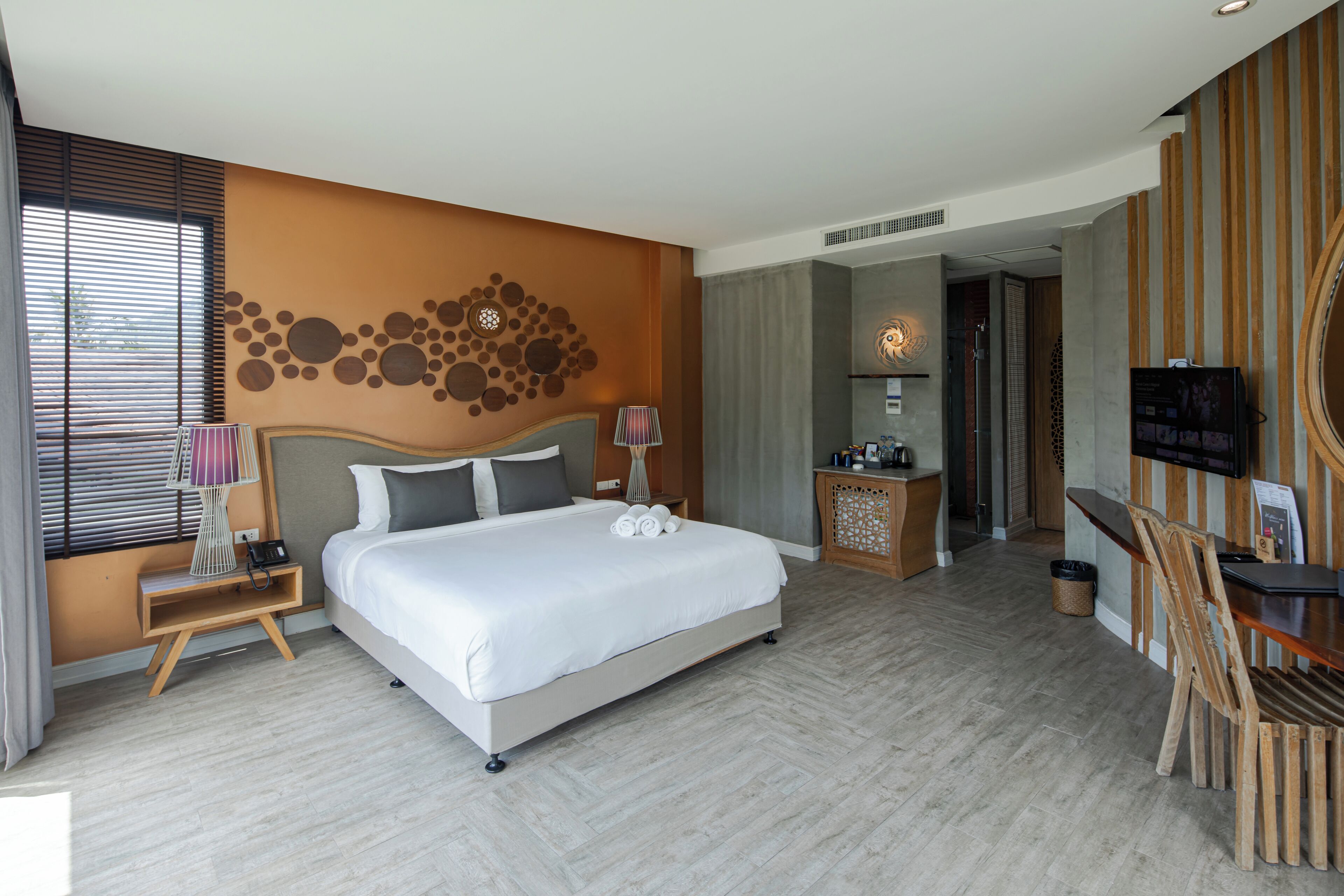 A hotel room with a large bed, bedside table, lamp, and a TV.