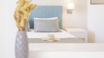 A neatly arranged bedroom with a bed, a bedside lamp, a decorative vase, and a hat on the bed.