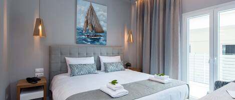 Een moderne slaapkamer met een groot bed, een nachtkastje, een schilderij van een zeilboot en uitzicht op de omgeving door een schuifdeur.