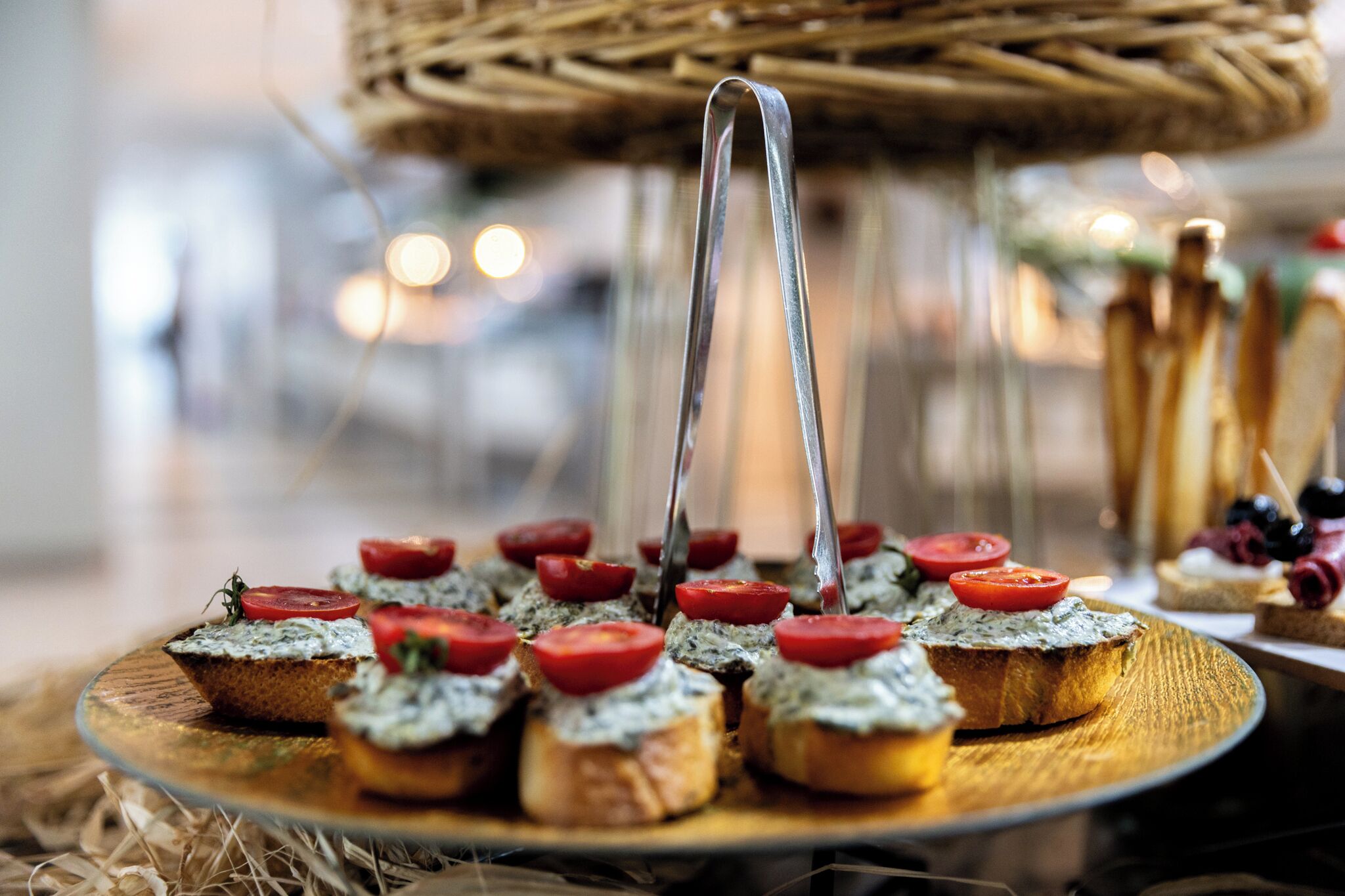 A wooden board with several pieces of bruschetta topped with tomatoes and a green spread.