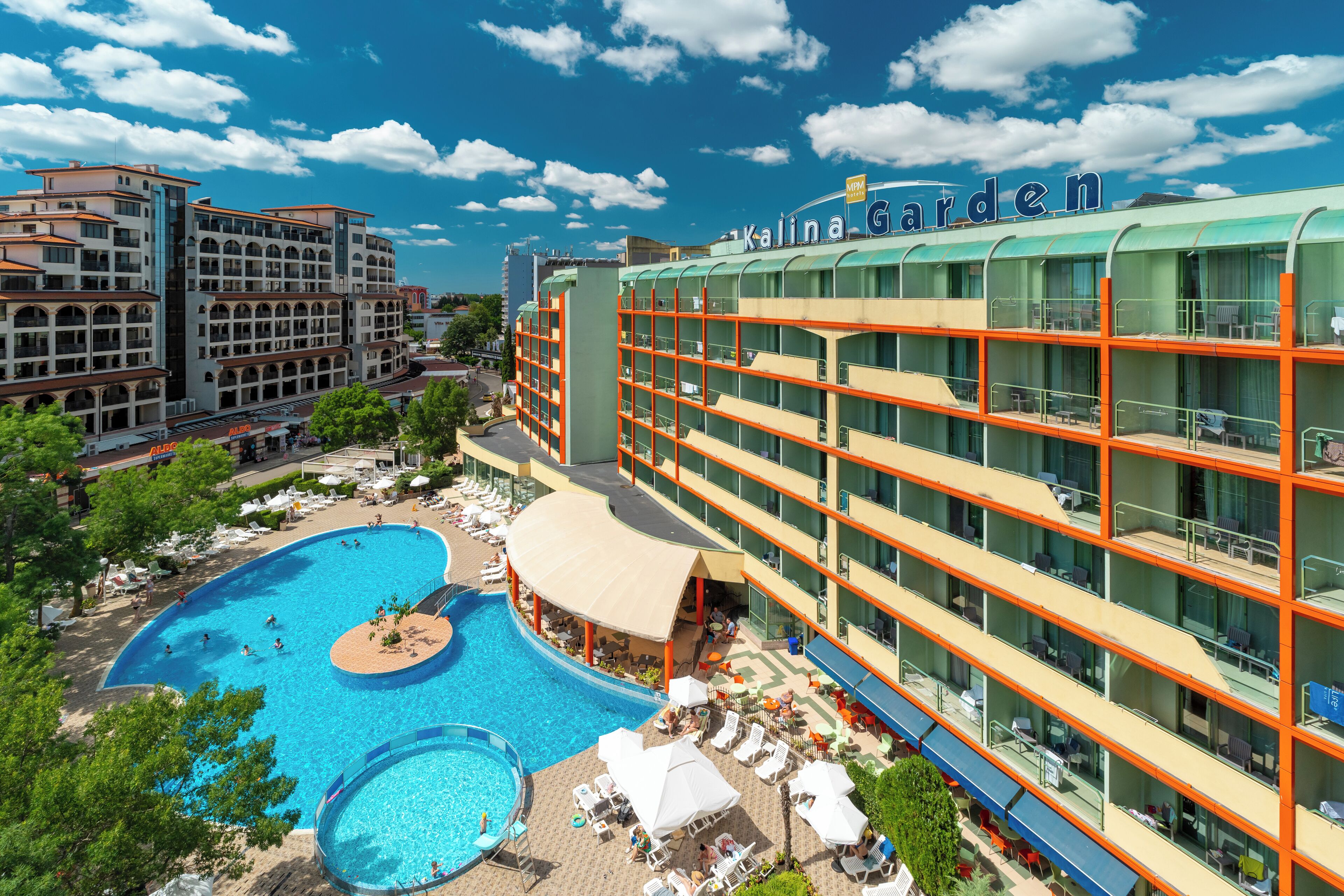 A hotel with a pool, multiple balconies, and a garden area.