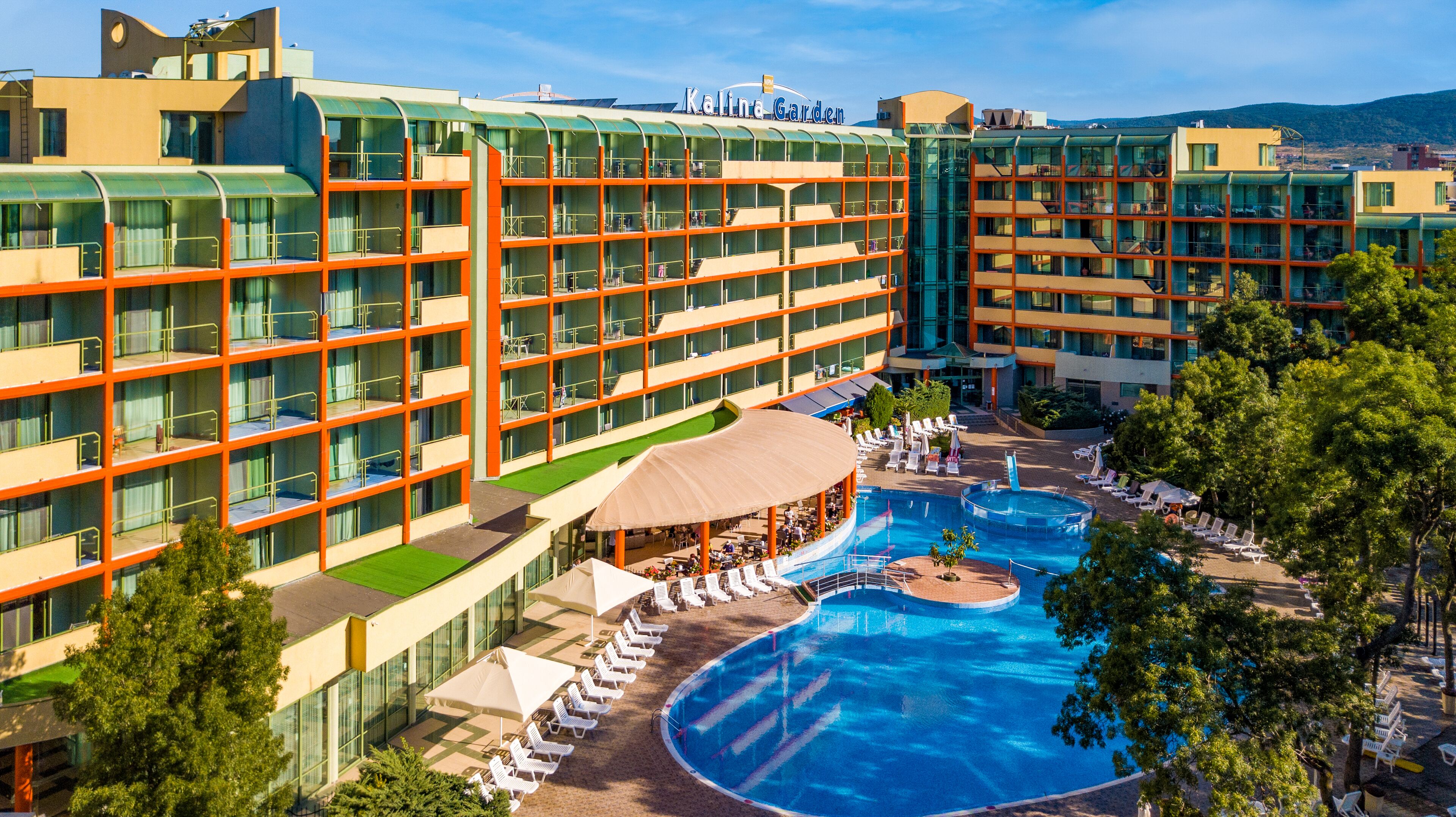 A hotel with multiple floors, a swimming pool, and outdoor seating areas.