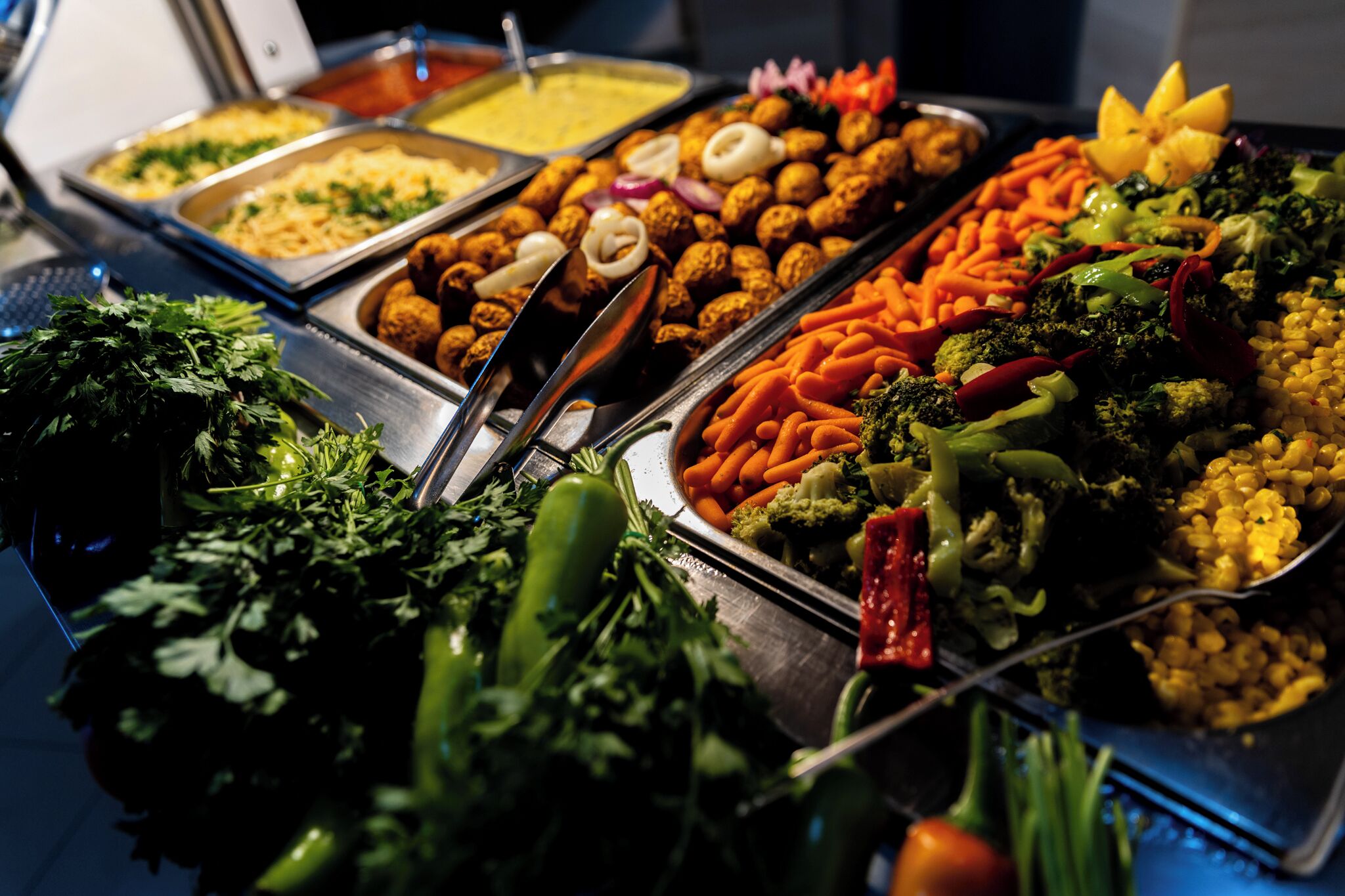 A buffet with various food items including vegetables, meats, and sauces.