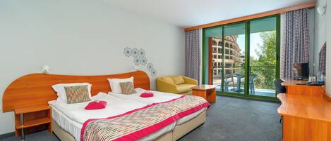 A hotel room with a large bed, a desk, a chair, and a view of the outside.