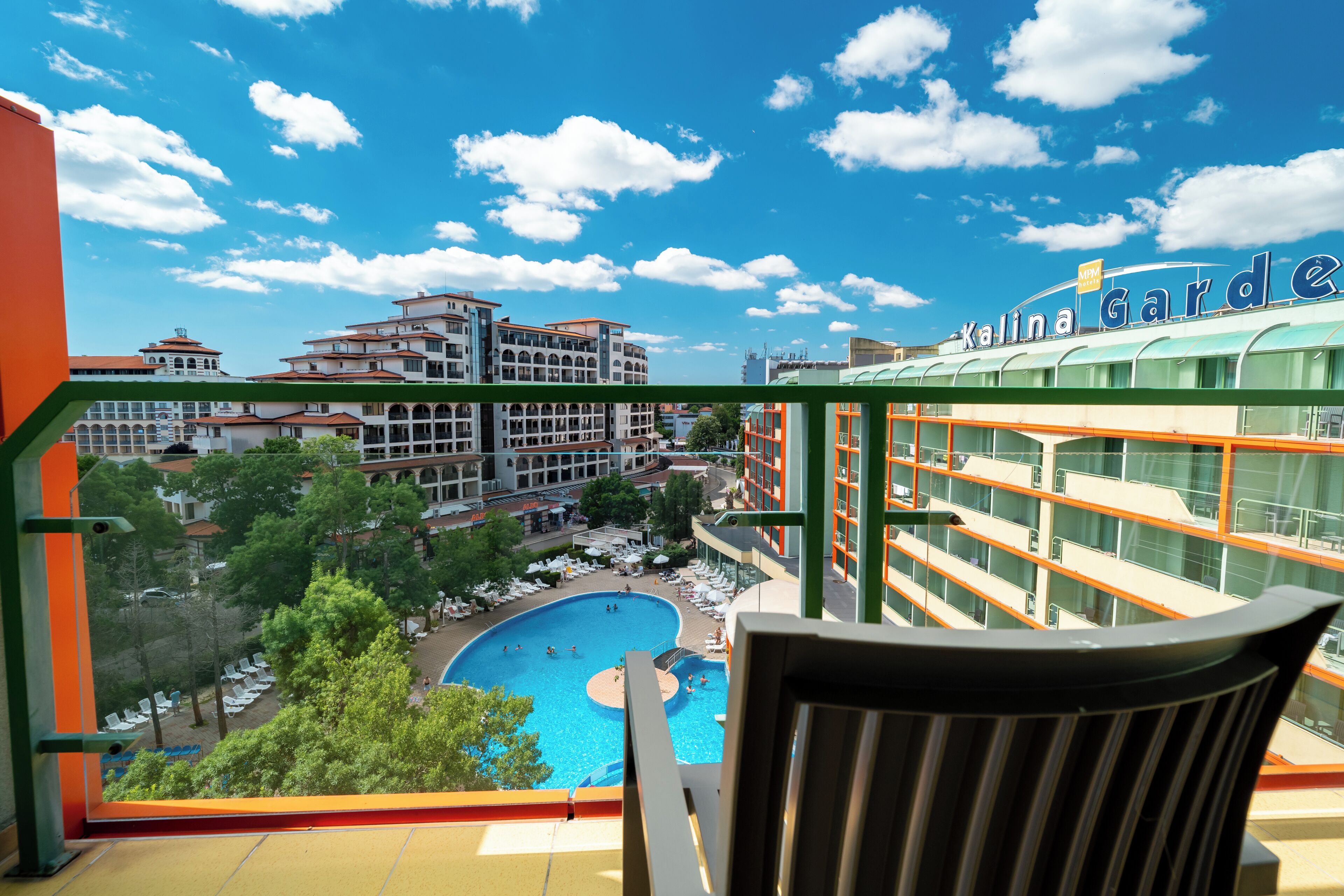 Un hotel con área de piscina, varias edificaciones y cielo despejado.