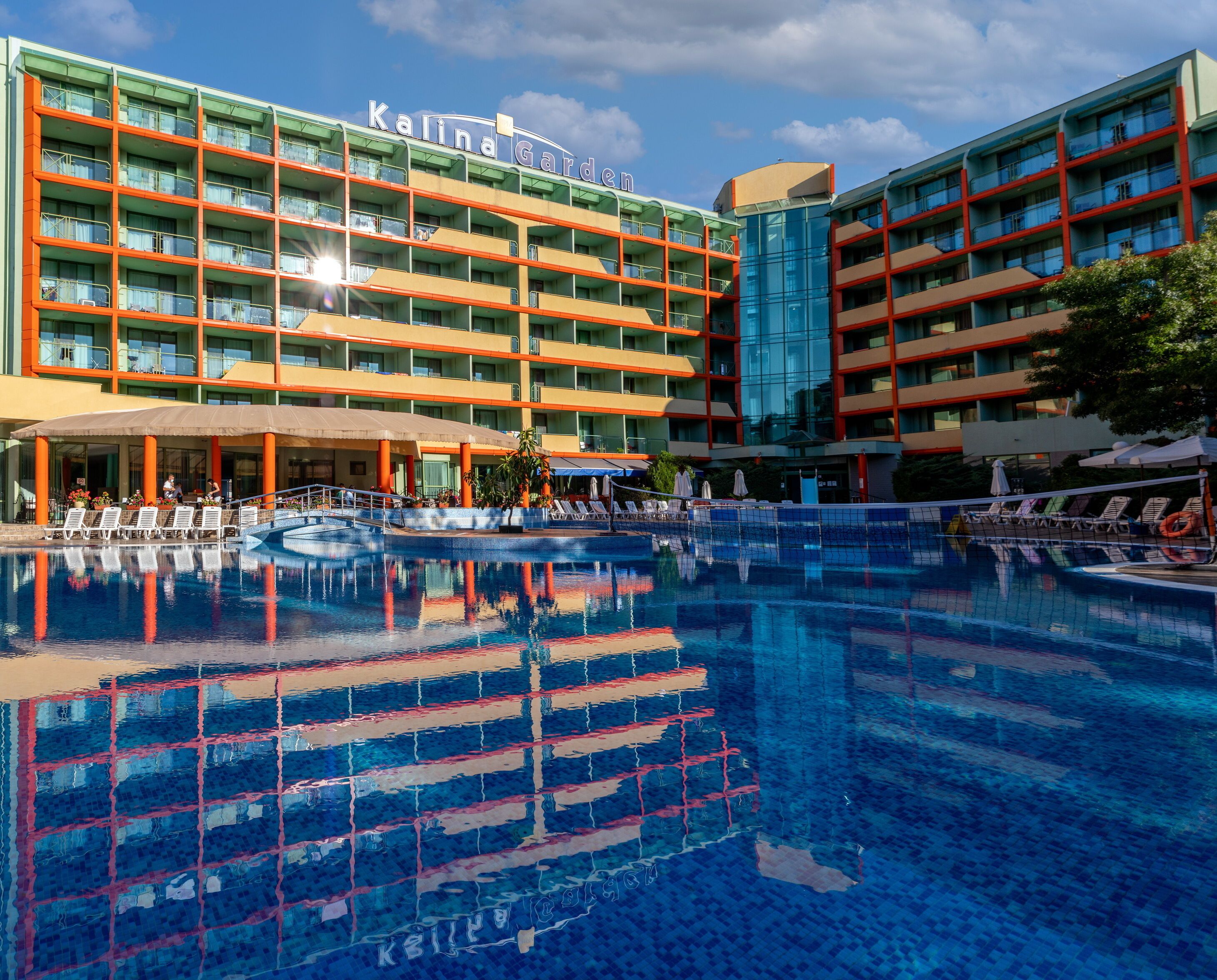 Un hôtel doté d’une grande piscine, de nombreux balcons et offrant une vue sur un ciel dégagé.