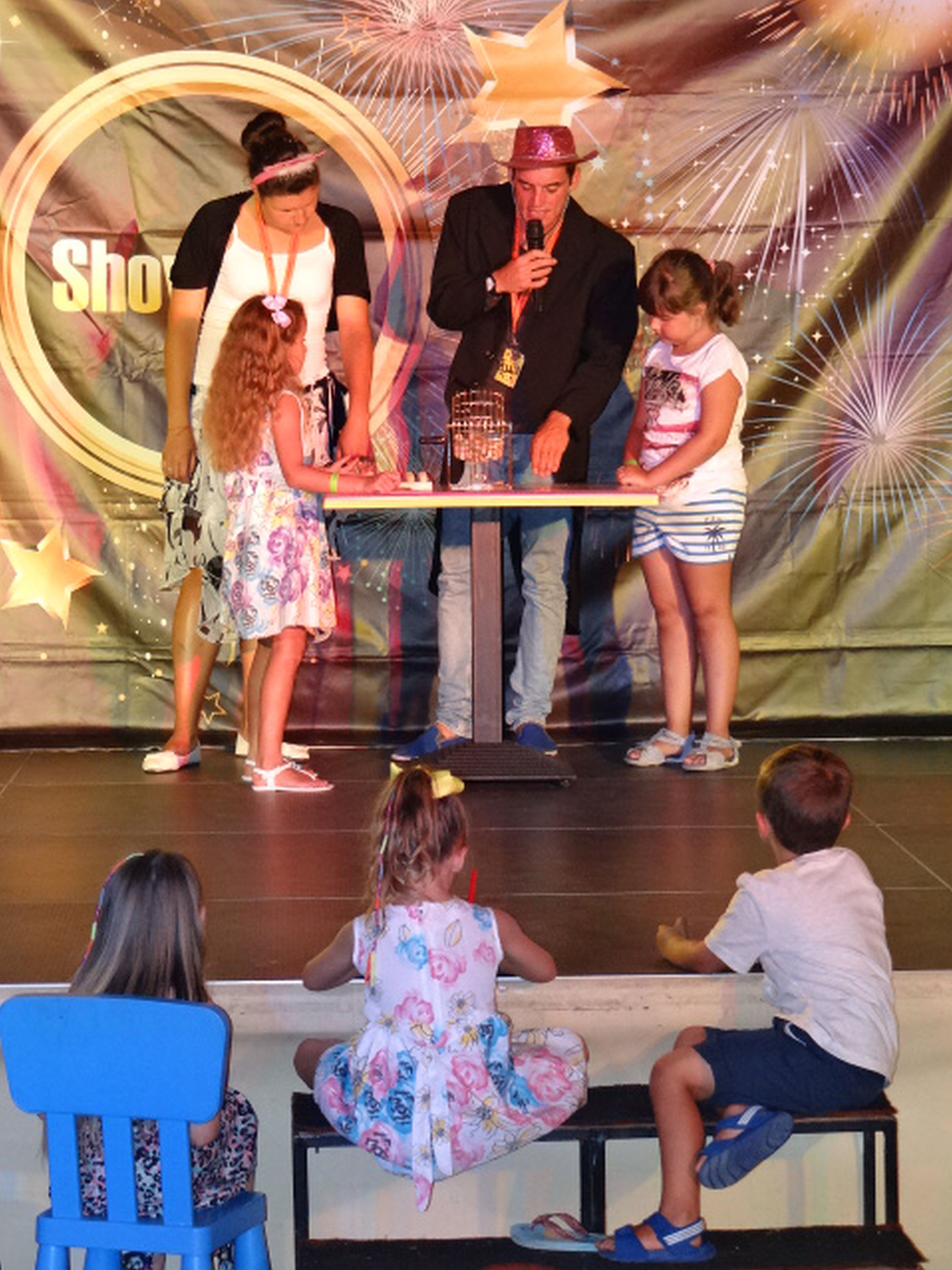 A stage with a group of people, including children and adults, engaged in an activity.