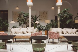 Un hall d’entrée avec un canapé, des fauteuils, une table basse et des plantes en pot.
