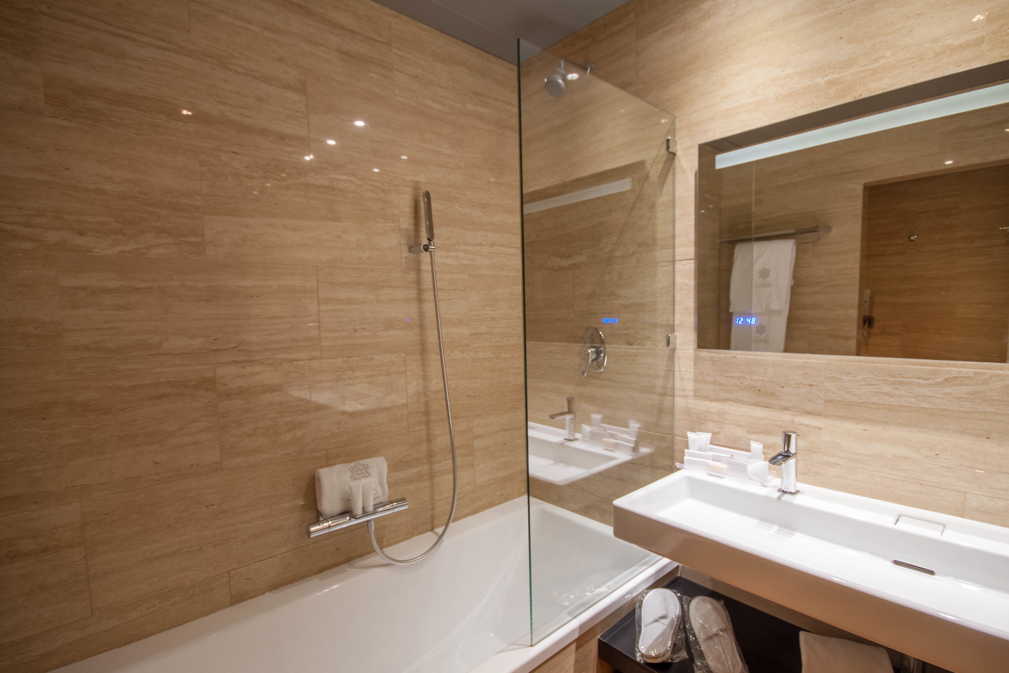 Un baño moderno con ducha vidriada, dos lavamanos y un espejo grande.