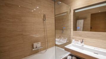 Un baño moderno con ducha vidriada, dos lavamanos y un espejo grande.