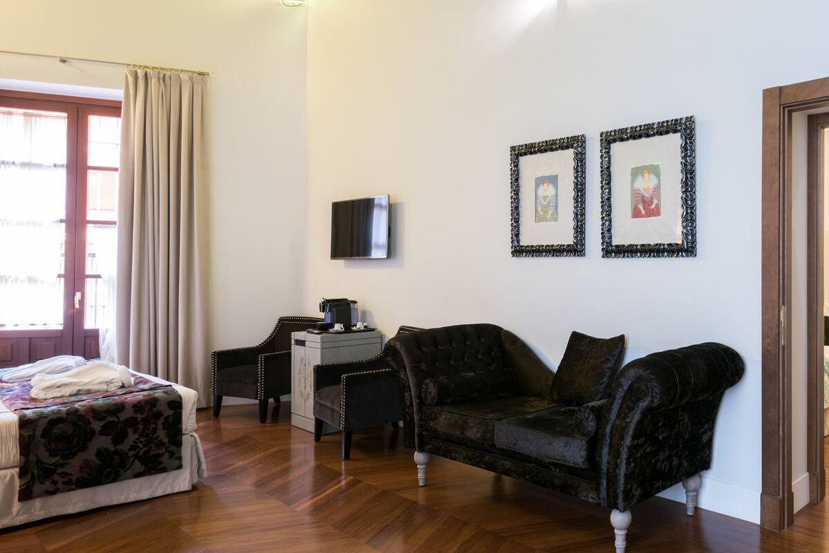 Ein Hotelzimmer mit einem Bett, einer Couch, einem Schreibtisch und zwei gerahmten Bildern an der Wand.