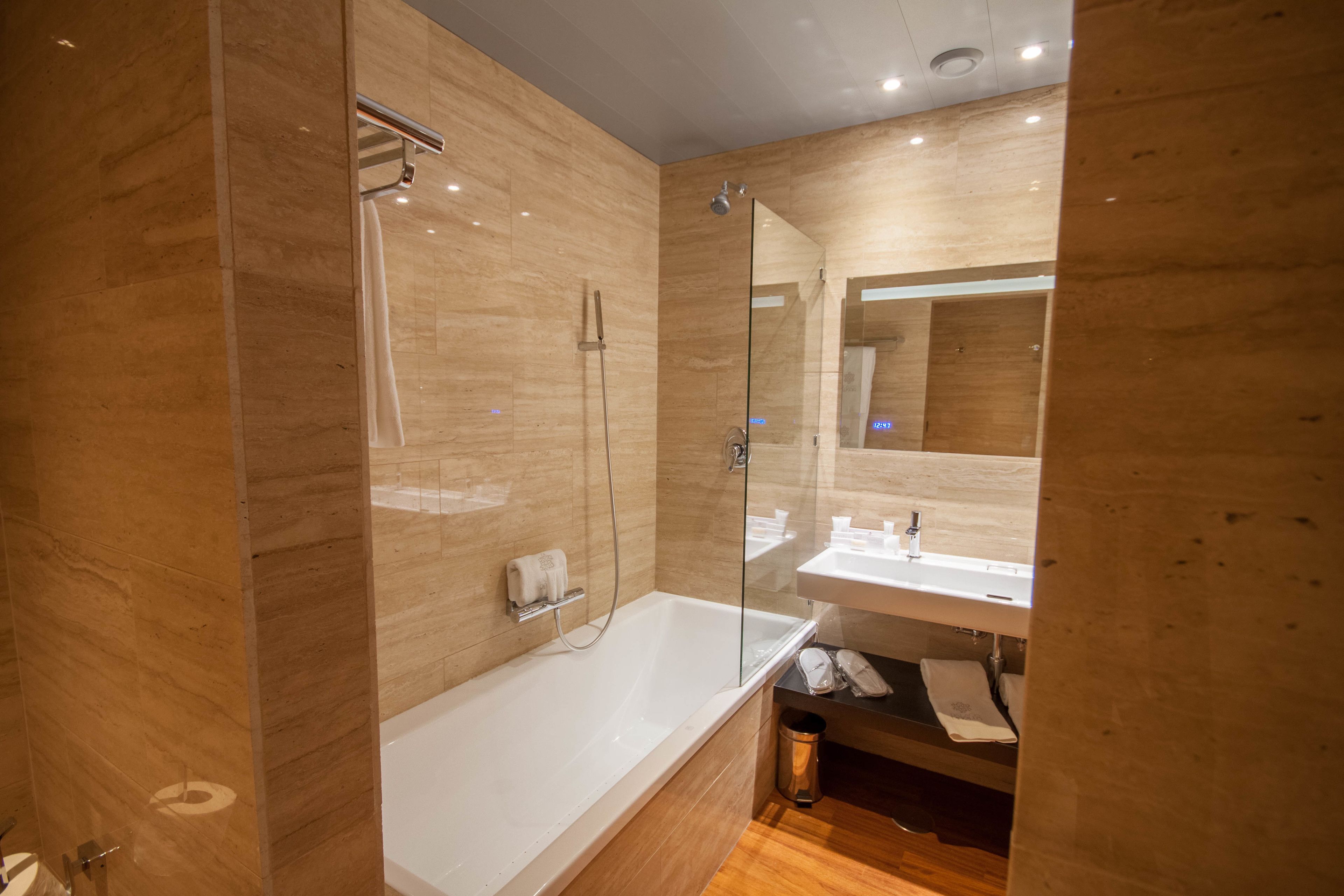 Un baño moderno con ducha envuelta en vidrio, una bañera blanca y un espejo grande sobre el lavabo.