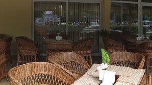 Un restaurante con mobiliario de mimbre y puertas de cristal.
