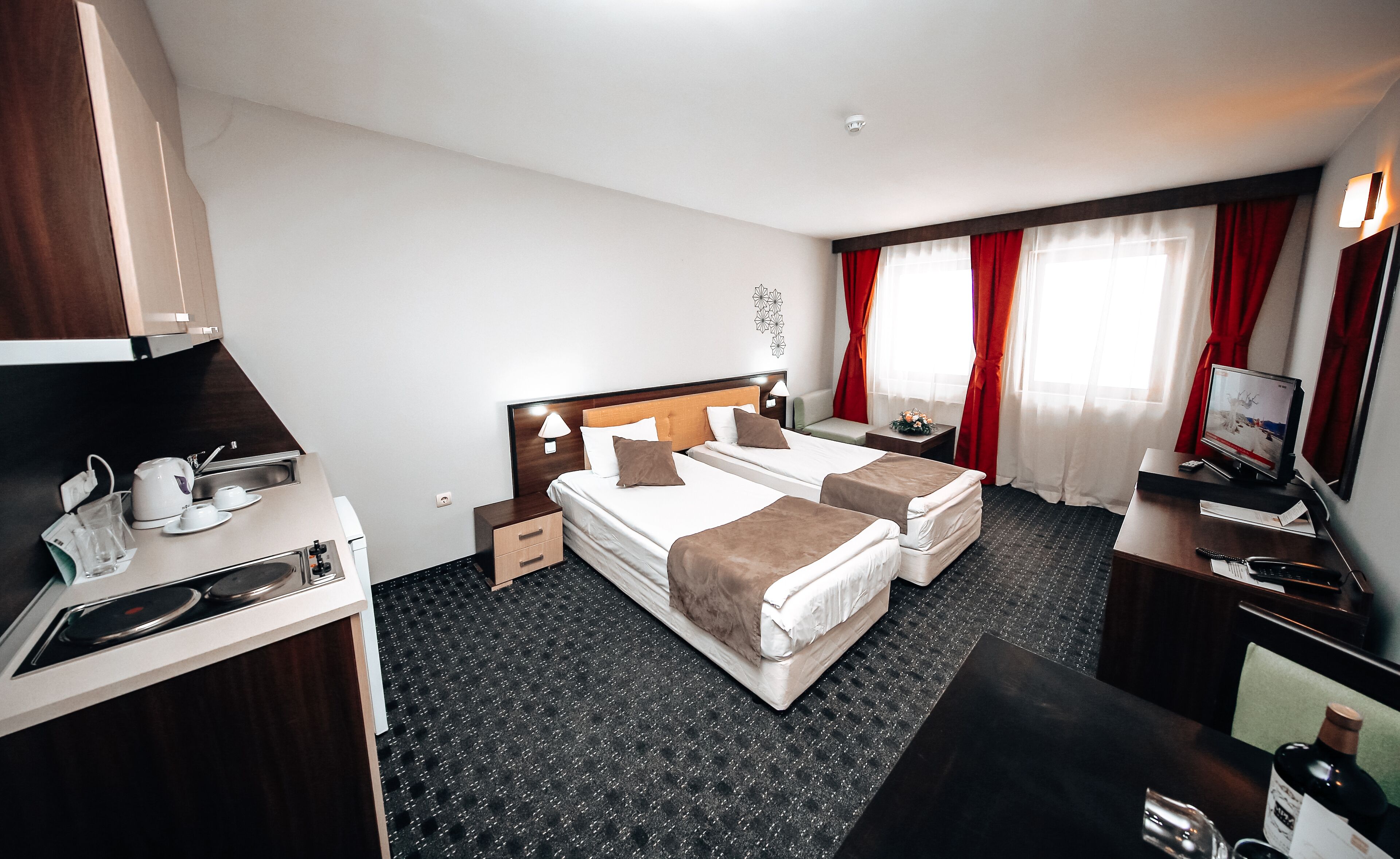 Une chambre d’hôtel avec deux lits, un bureau avec un ordinateur, une télévision et un minibar.