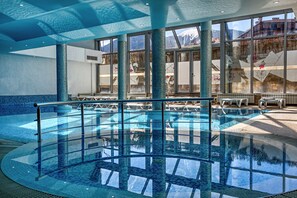 Una piscina cubierta, tumbonas, socorrista en las instalaciones