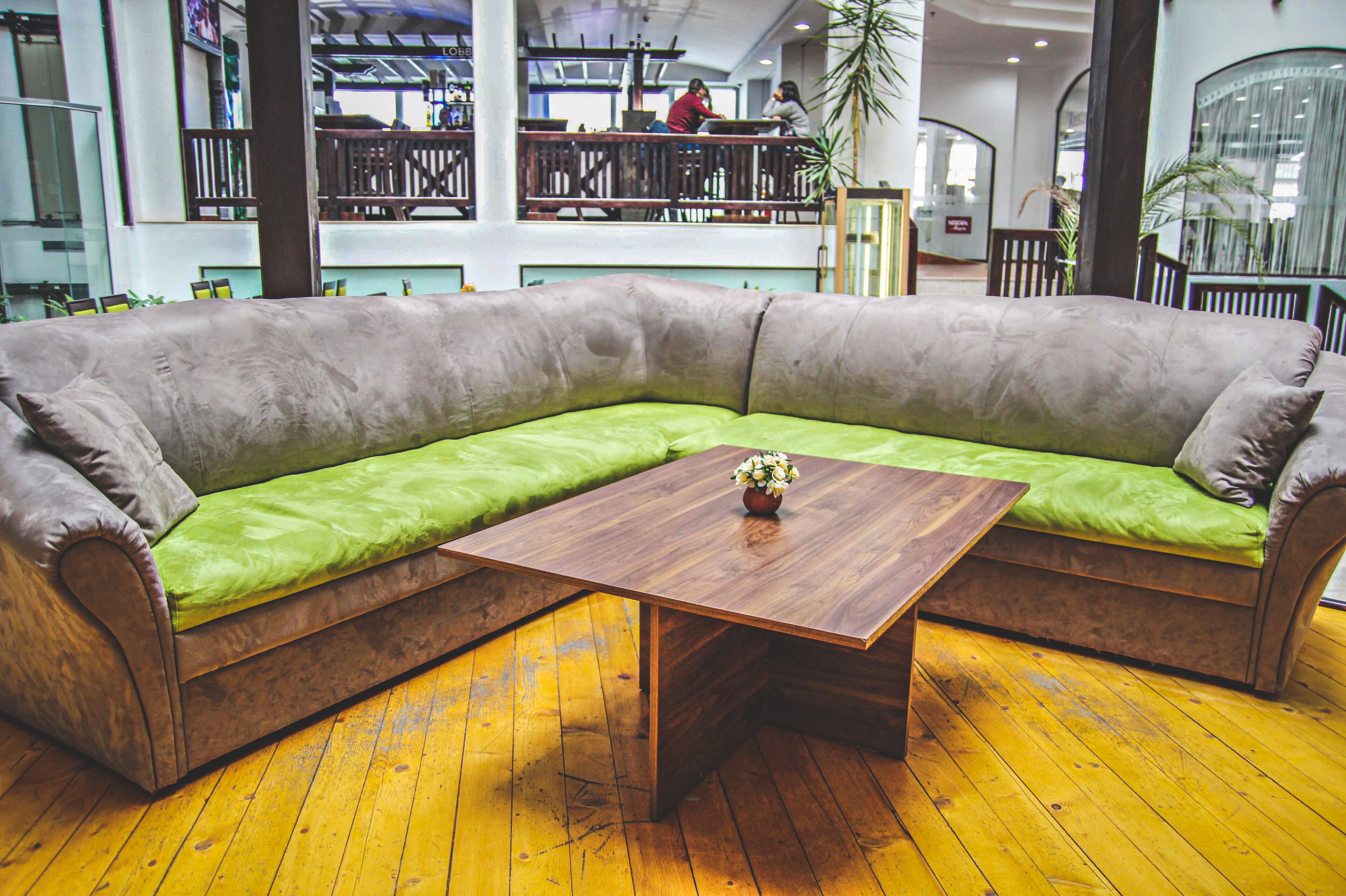 Een modern interieur met een ruime hoekbank, een houten salontafel en een geel houten vloer.
