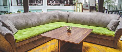 Een modern interieur met een ruime hoekbank, een houten salontafel en een geel houten vloer.