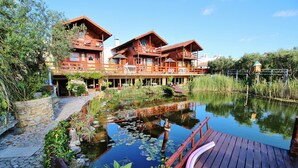 Un chalet en bois avec un étang, une terrasse en bois et un chemin en pierre.