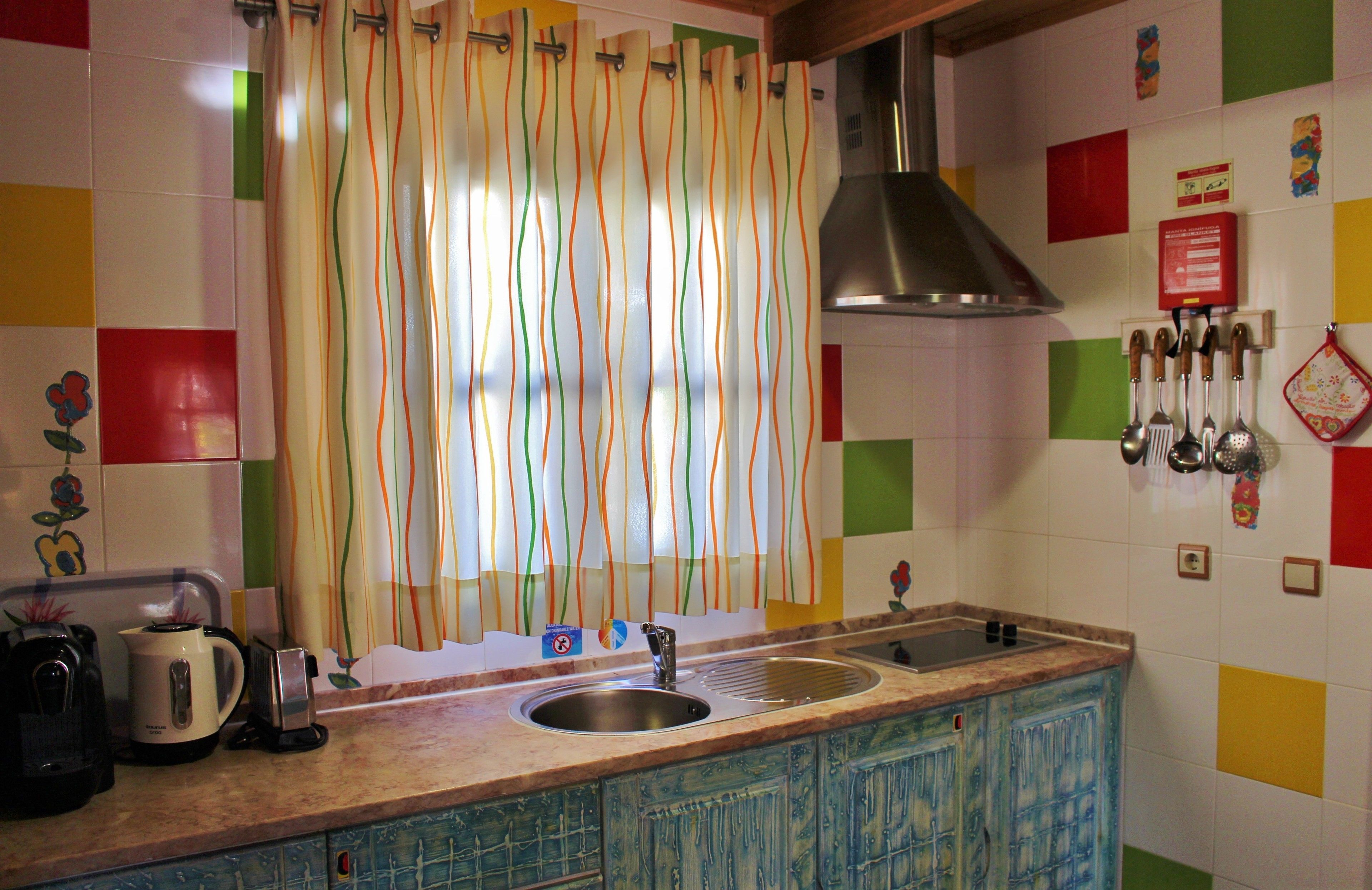 Una cocina con un lavamanos, una tetera y una estufa.