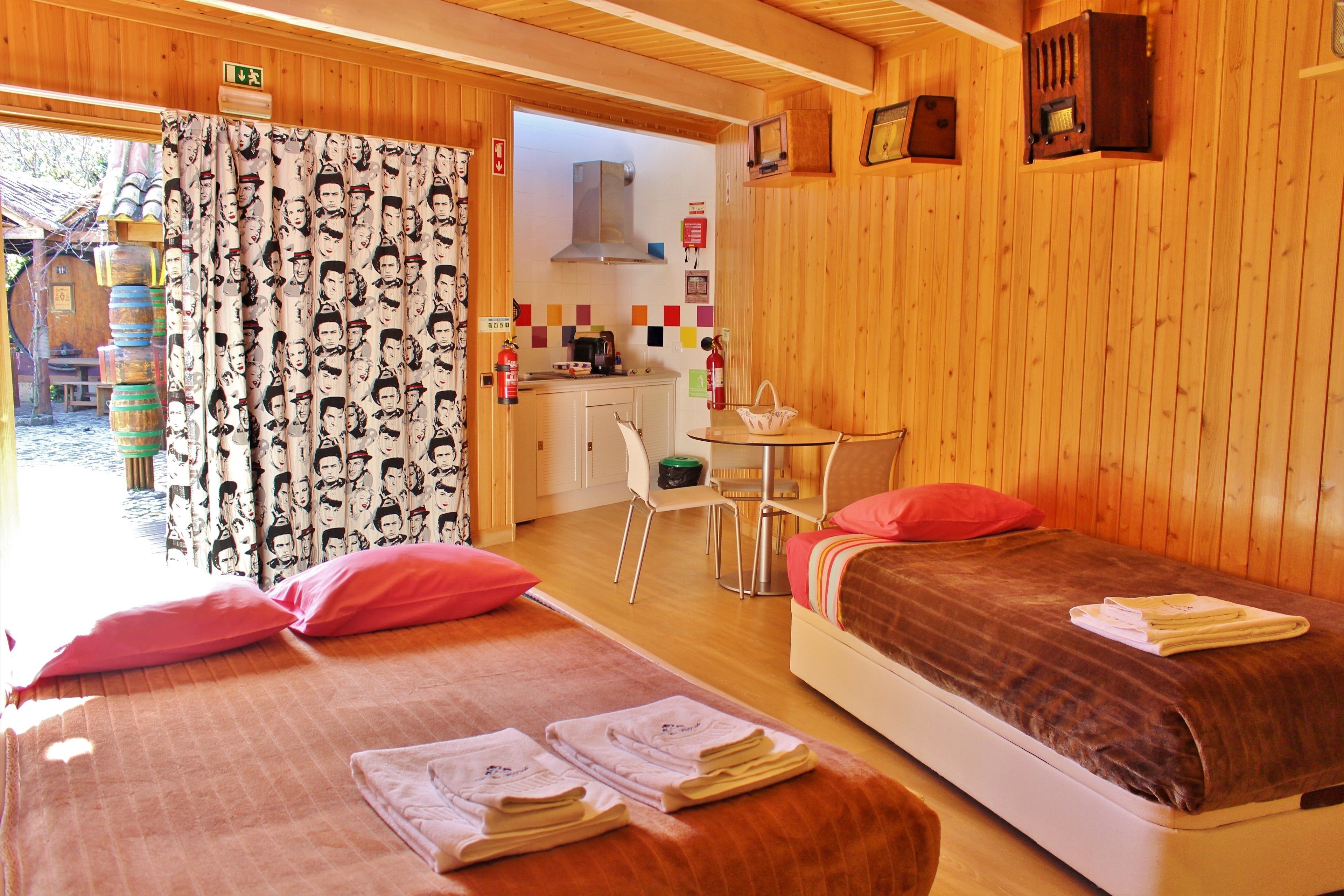 A cozy room with two beds, a small kitchenette, and a view of the outside.