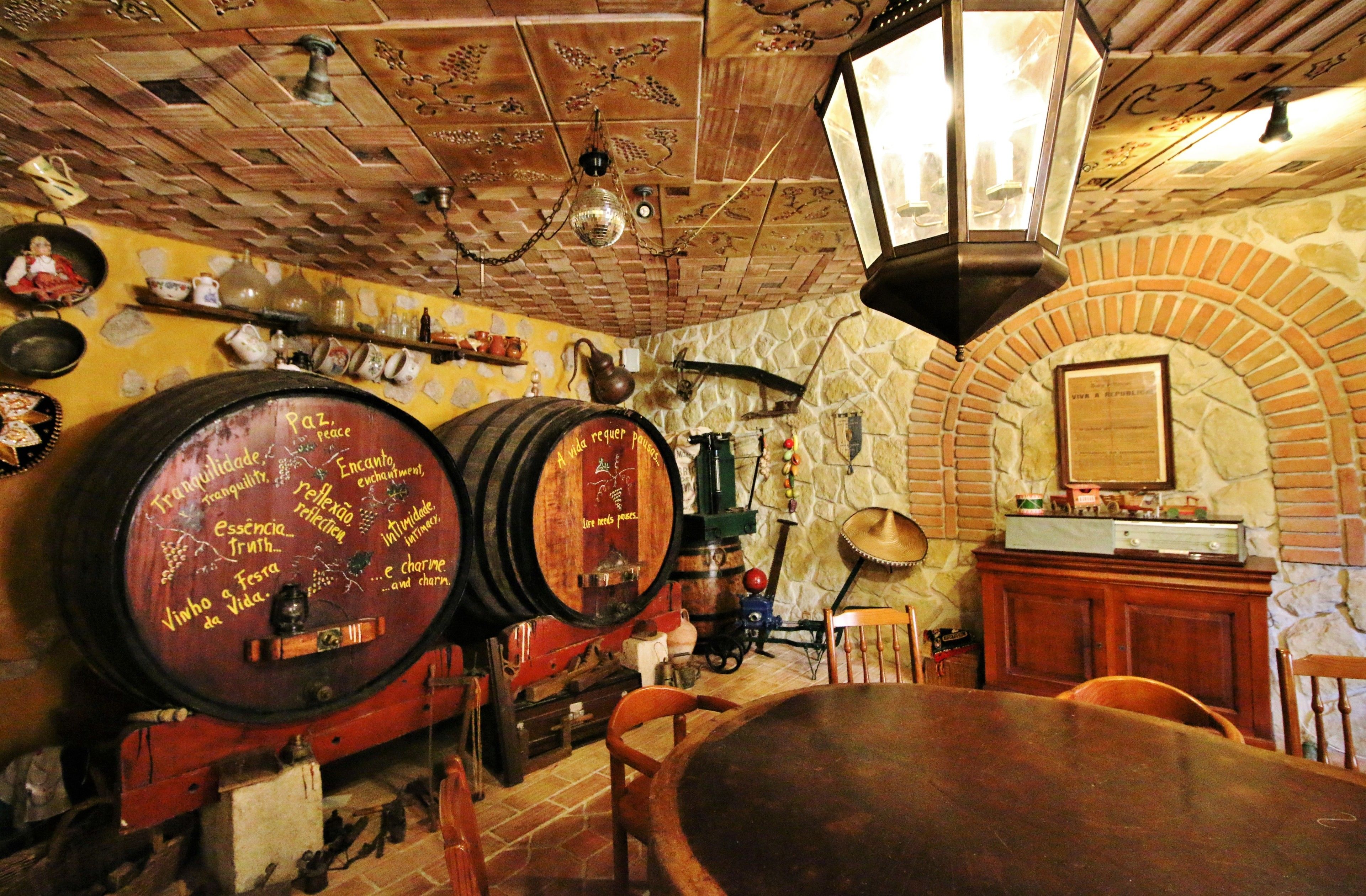 Een rustiek interieur met houten vaten, een stenen muur en een traditionele kroonluchter.