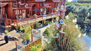 Un hôtel en bois doté de balcons, d’un espace extérieur aménagé avec des sièges et d’un jardin agrémenté de nichoirs.