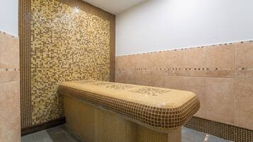 Une salle de bain avec des murs recouverts de mosaïques, un banc carrelé et un sol carrelé.