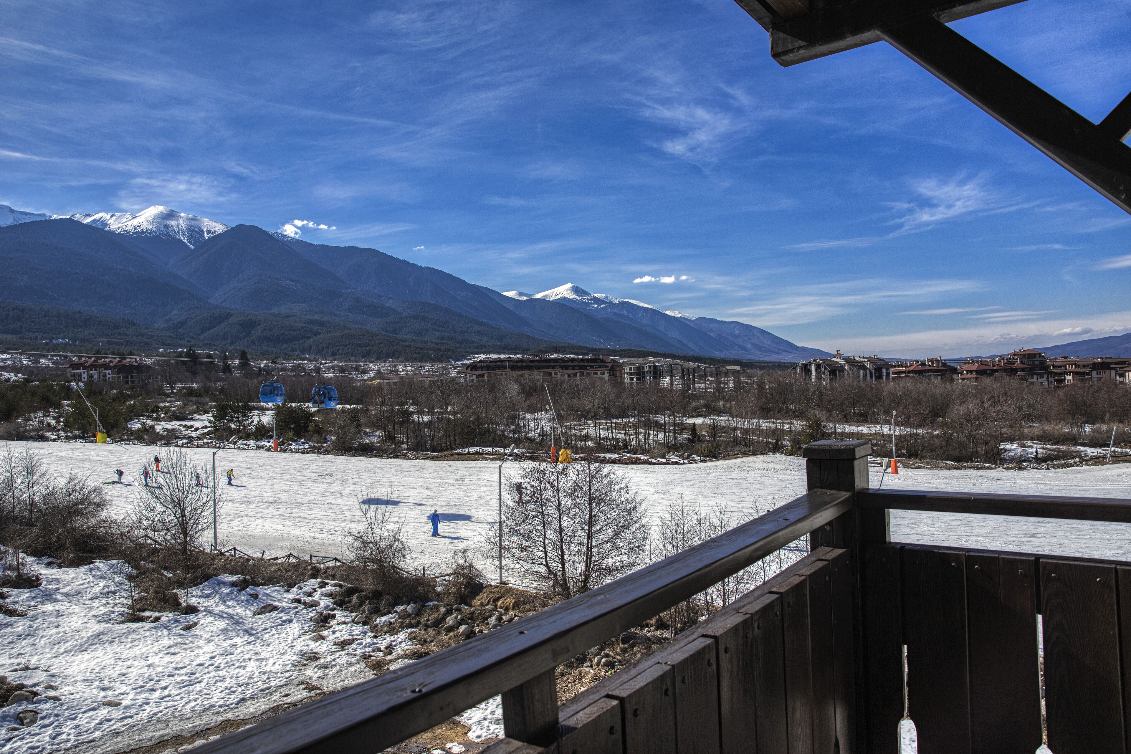 A view from a wooden deck overlooking a snowy landscape with mountains in the background.