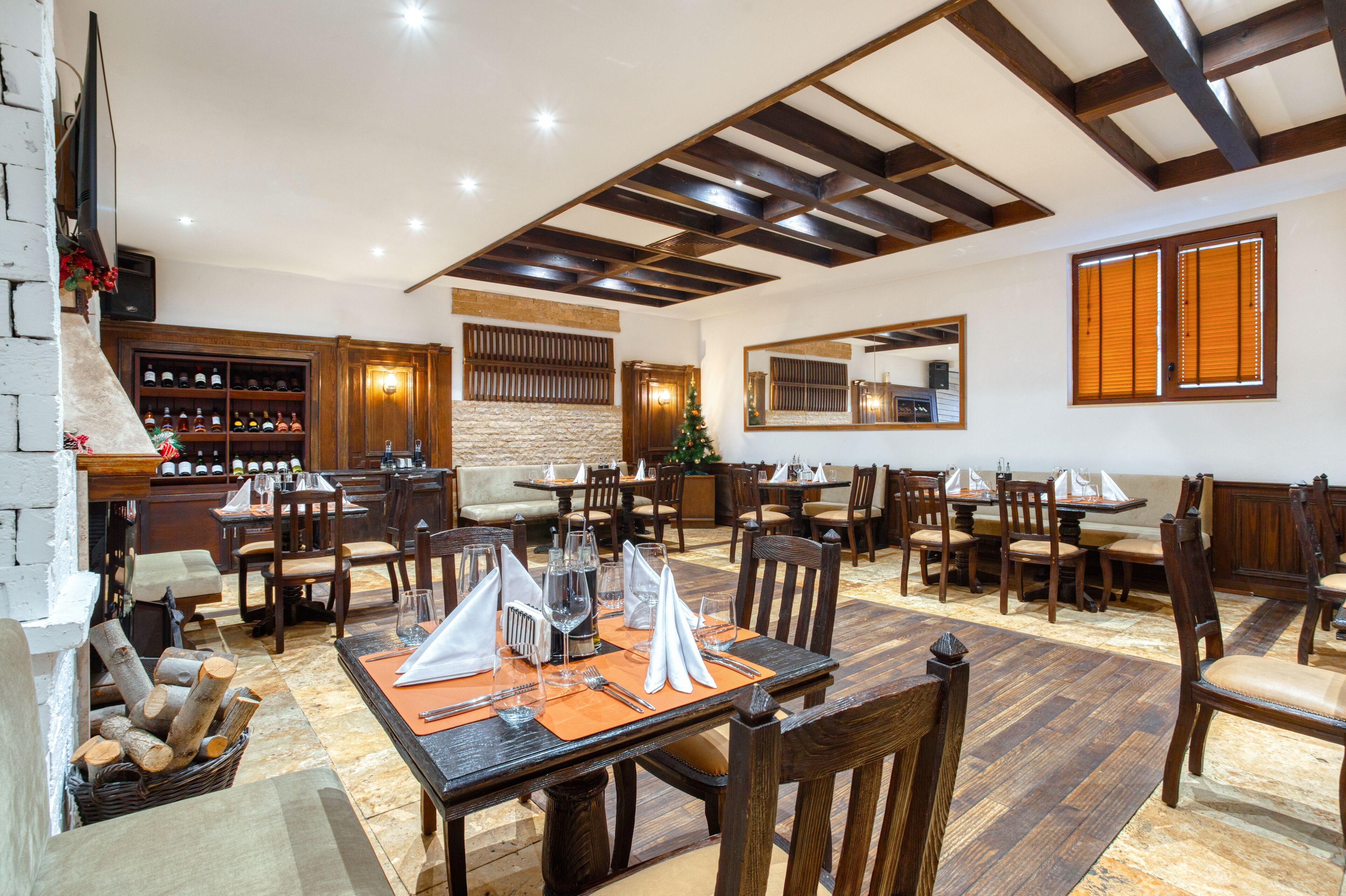 Un comedor con mesas y sillas de madera, una chimenea y una barra con botellas.