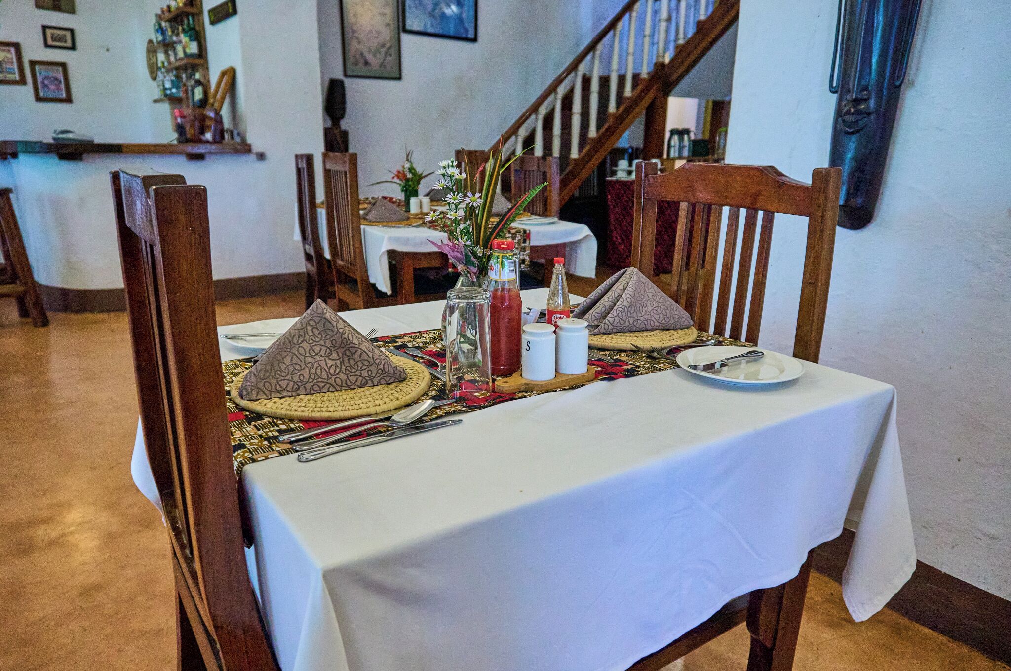 A dining table set with traditional hats, a vase with flowers, and condiments.