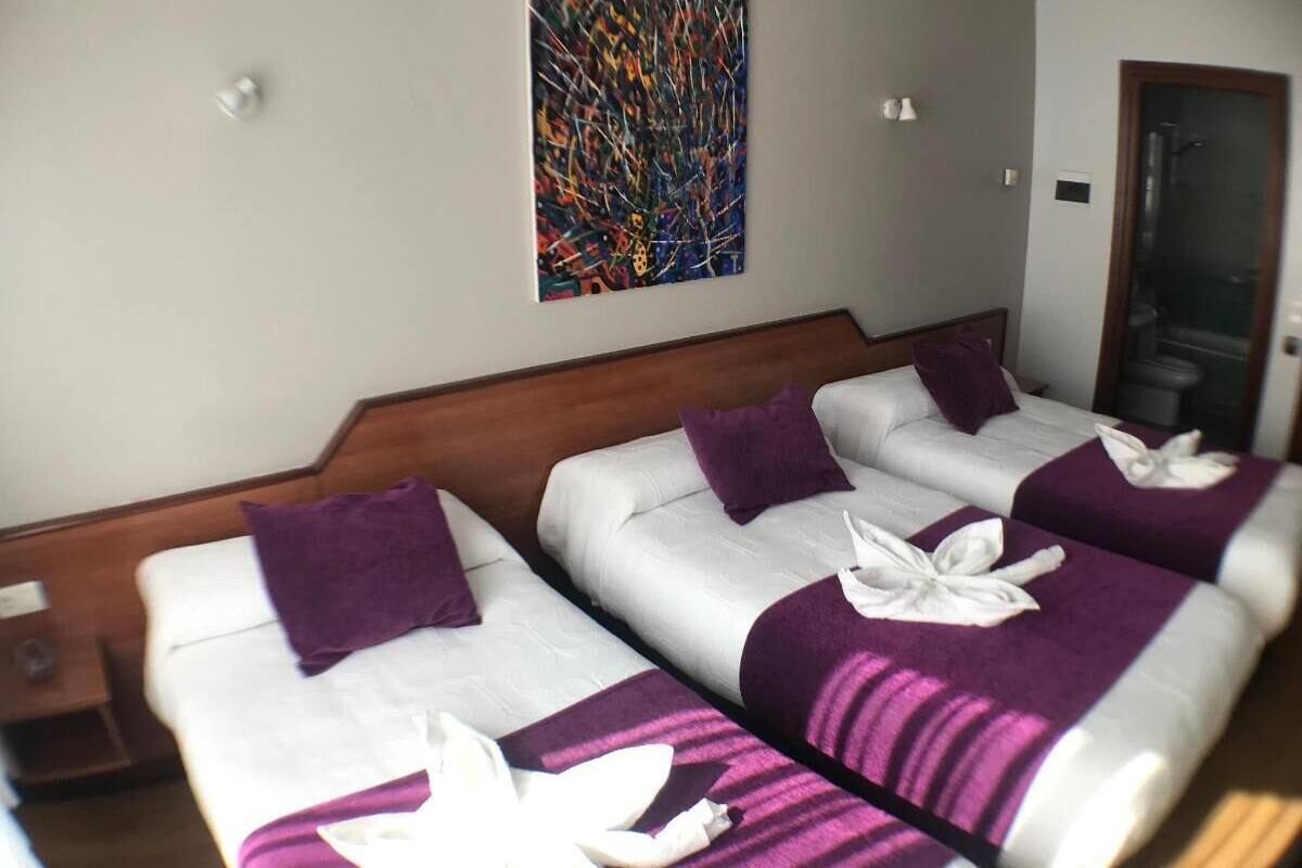 Une chambre d’hôtel avec deux lits, chacun étant recouvert d’une couverture violette et agrémenté de serviettes blanches.