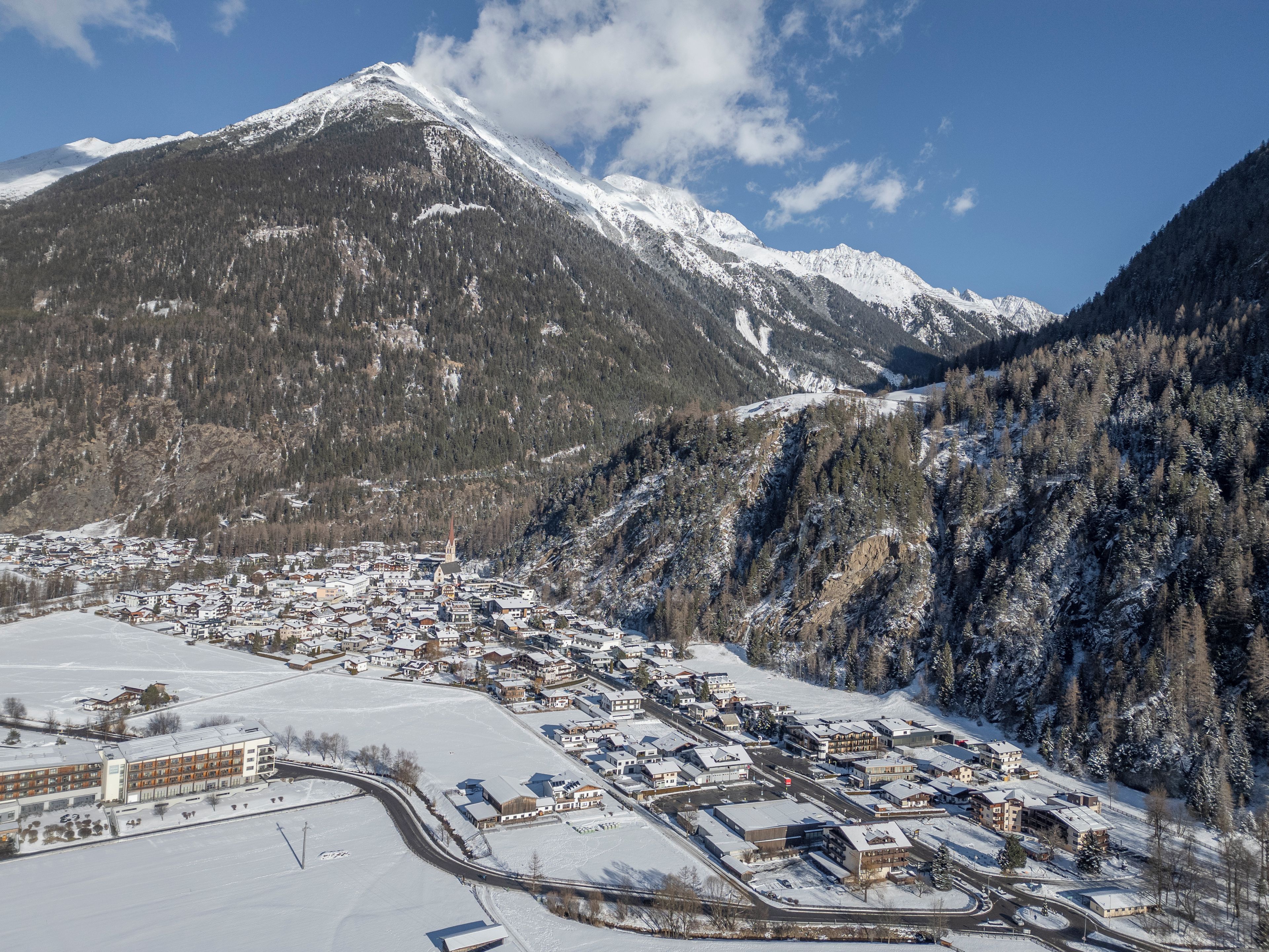 A town with a church, surrounded by snow-covered mountains and a clear sky.