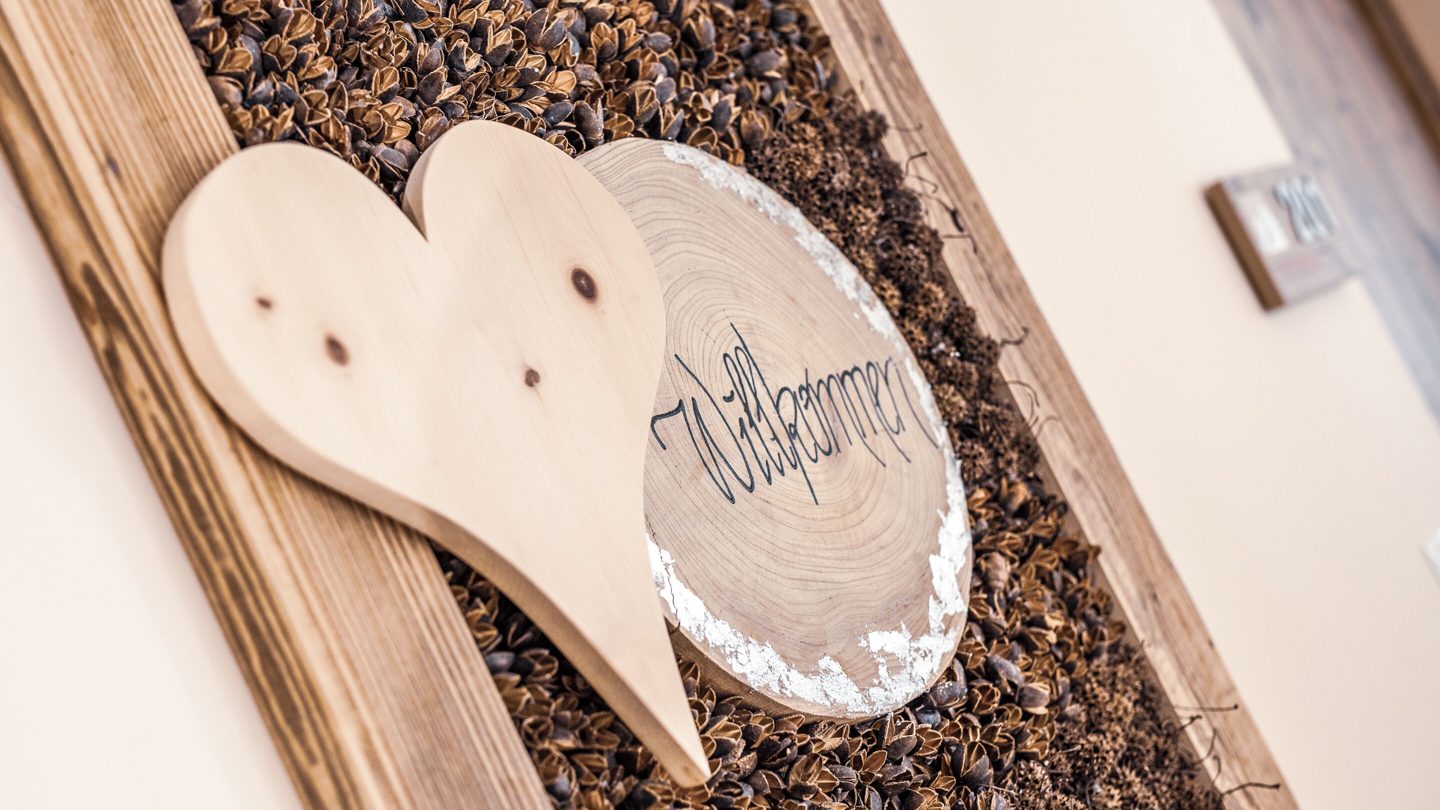 A wooden heart-shaped sign with a name, surrounded by scattered seeds and a wooden spoon.
